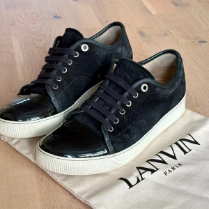 Svarta Lanvin sneakers - Säljer ett par stilrena Lanvin Cap Toe som är i riktigt bra skick.                                                             Storlek: 42,5 UK7 (stora i storleken)                                  Og: Dustbag                                                                  Pris: 2139kr ( kan diskuteras vid snabbt köp)         Fråga bara på vid minsta fundering 🙌