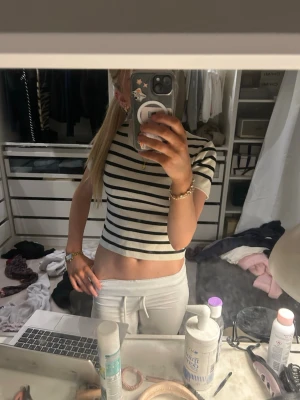 Randig croppad t-shirt i bomull - Säljer en croppad t-shirt med svarta och vita ränder. T-shirten har korta ärmar och rund halsringning. Materialet känns som bomull och toppen har en slim passform som sitter snyggt på kroppen.