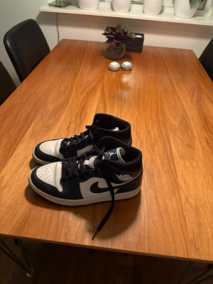 Nike Air Jordan 1 Mid blå/vit - Snygga Nike Air Jordan 1 Mid sneakers i svart och vitt med klassisk swoosh-logga på sidan. Riktigt Bra skick bortsett från att dom är ”creesade”, vilket skor blir men men:)