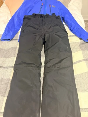 Svarta täckbyxor Everest - Säljer ett par svarta täckbyxor från EverestByxorna har justerbar midja med kardborre, förstärkta knän och dragkedjor vid bensluten. Perfekta för vinterns alla äventyr i snön. Materialet är slitstarkt och vattenavvisande. NYPRIS: 3000kr PRIS: 650kr