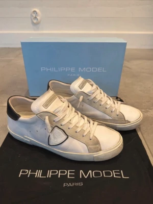 Philippe Model vita sneakers - Säljer ett par Phillipe modell i storlek 42. De är lite trasiga vid hälen men annars så finns de inga defekter.
