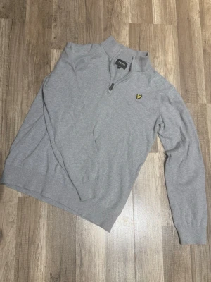 Grå halvzip från Lyle & Scott Junior - Snygg grå tröja från Lyle & Scott Junior med halv dragkedja och klassisk gul logga på bröstet. Finns ett litet hål på vänster arm. Inga prisförslag är dumma!