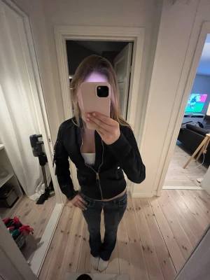 Marinblå bomberjacka - Snygg marinblå bomberjacka med guldfärgade detaljer och dragkedja framtill. Jackan har ribbade muddar vid ärmar och midja. Nypris på dessa jackor är ca 2500kr 