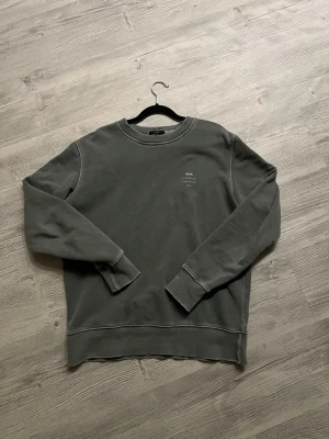 Mörkgrön sweatshirt från Neuw Stockholm - En stilren mörkgrön sweatshirt från Neuw med rund halsringning och diskret vit text på bröstet. Tröjan har långa ärmar, ribbade muddar och är gjord i mjuk bomullsblandning. Perfekt för en avslappnad och trendig look. Så klart kan priset diskuteras.
