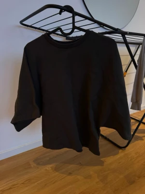 Svart oversized t-shirt - En svart oversized t-shirt med rund hals och korta ärmar. T-shirten har en enkel och clean design utan tryck eller mönster, perfekt för en avslappnad stil. Tillverkad i mjuk bomull som känns skön mot huden.