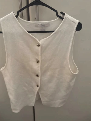 Vit väst med knappar från Amisu - Stilren vit väst från Amisu med klassisk v-ringning och snygga silverfärgade knappar framtill. Västen är ärmlös och har en enkel, rak passform som passar till många olika looks. Perfekt att styla över en skjorta eller t-shirt. För fler bilder/information skriv gärna, priset kan justeras 🤗❤️
