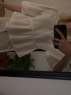 Vit blus med puffärm och struktur - Säljer en vit blus med puffiga trekvartsärmar och markerad midja. Blusen har en strukturerad yta och en avslappnad passform, perfekt för en trendig och stilren look. Passar till både jeans och kjol.