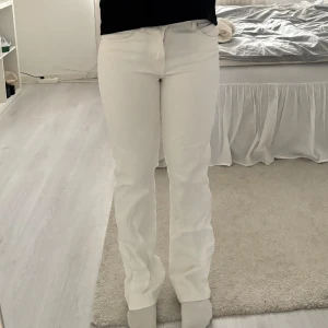 Vita raka jeans med hög midja - Säljer ett par vita jeans med rak passform och hög midja. Jeansen har klassisk femficksdesign och stängs med knapp och dragkedja. 