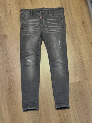 Grå jeans från Dsquared2, storlek 40 - Säljer ett par gråa dsquared2 jeans med slitningar. Köpte dom begagnade av en vän och jag har endast använt dom en gång. Dom är i bra skick, inga fläckar, missfärgningar eller hål som inte är en del av designen