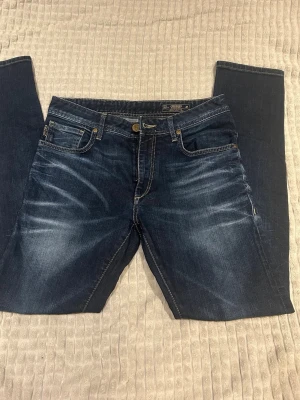 Jack and Jones  - Passar dom inte!!                                                 96cm i längs//41cm i midjan//                       Snygga mörkblå jeans med raka ben och diskreta slitningar framtill. Klassisk femficksmodell med guldfärgade detaljer och kontrastsömmar. Perfekta för en avslappnad och trendig look.