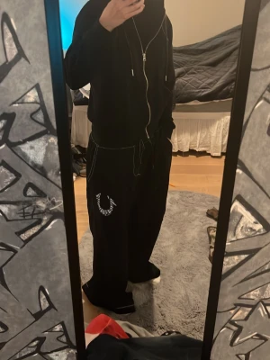True religion sweatpants  - Säljer ett par svarta mjukisbyxor med bred passform och vita kontrastsömmar. Byxorna har ett stort vitt tryck på ena benet och dragsko i midjan för skön passform. Perfekta för chill dagar eller streetwear-stil. Använda några gånger.☺️