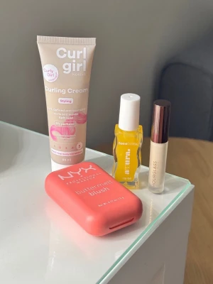 Skönhetspaket med blush, olja & kräm - Paket med NYX Butter Melt Blush i korallrosa, Curl Girl Nordic Curling Cream för lockigt hår, Murré Face & Lips Oil samt Hourglass mini concealer. 
