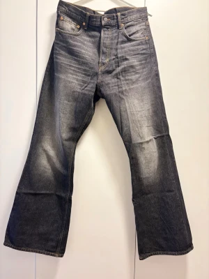 Weekday Time Loose Bootcut Jeans - Ett par svarta/gråa jeans från Weekday i storlek 32/34. Byxorna är knappt använda och i mycket bra skick