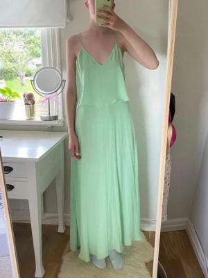 Mintgrön långklänning med smala axelband - Luftig och flowy långklänning i mintgrönt med smala axelband och v-ringning. Jättefin långklänning från Zara💚 Jag på bilden är 172 cm lång med långa ben och den är lagom längd på mig (se bilder).  Klänningen är begagnad så är därför osäker på hur mycket den används, men den är lite nopprig (se bilder), men det är inget större problem🥰