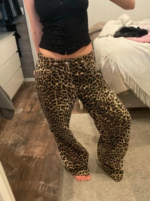 Leopardmönstrade vida jeans - Säljer ett par riktigt snygga leopardmönstrade jeans med låg midja och raka, vida ben. Jeansen har klassisk femficksmodell och coolt djurmönster i brunt, svart och beige. Perfekta för dig som vill sticka ut och addera edge till din outfit.