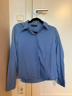 Blå skjorta  - En stilren blå skjorta från Mari Philippe, enkel och snygg design som funkar till många looks.