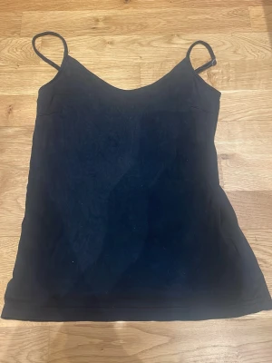Svart linne💕 - En enkel och stilren svart linnetopp med smala axelband och v-ringad hals. Perfekt att matcha med jeans eller kjol för en clean look. Materialet känns mjukt och lätt mot huden. Använder inte längre, det går inte att spänna in på vänstra sidan med den funkar bra ändå😊💕
