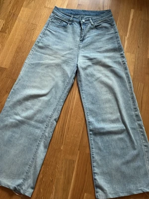 Ljusblåa vida jeans med hög midja - Säljer ett par ljusblå jeans med breda ben och hög midja. Klassisk femficksmodell i mjukt denimtyg. Perfekta för en avslappnad och trendig look. Passar dig som gillar loose fit och retrostil.