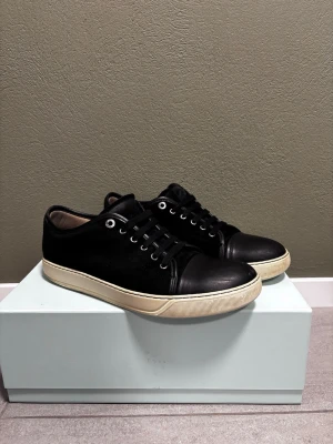 Lanvin nappa cap toe  - Jag säljer mina Lanvin nappa cap toe i färgen svart. Skorna är lite slitna på Cap toe och under sulan men annars så är mockan och passformen bra. Storlek 44 / 10   Originalbox, dustbag och använda orginalsnören följer med vid köp.