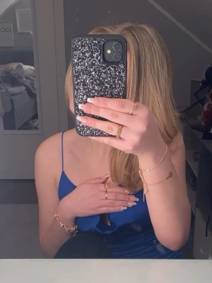 Kornblå linnetopp med tunna band - Snygg kornblå linnetopp med tunna axelband och draperad front. Toppen har en enkel, stilren design och är tillverkad i ett mjukt, stretchigt material som känns skönt mot huden. Perfekt att styla till jeans eller kjol för en fräsch look.