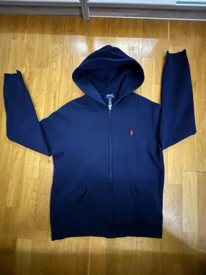 Mörkblå hoodie från Polo Ralph Lauren - Säljer en mörkblå ralphlooren hoodie med röd logga i storlek S. Hoodien har använts max 1-3 gånger. Hör av dig om du är intresserad!