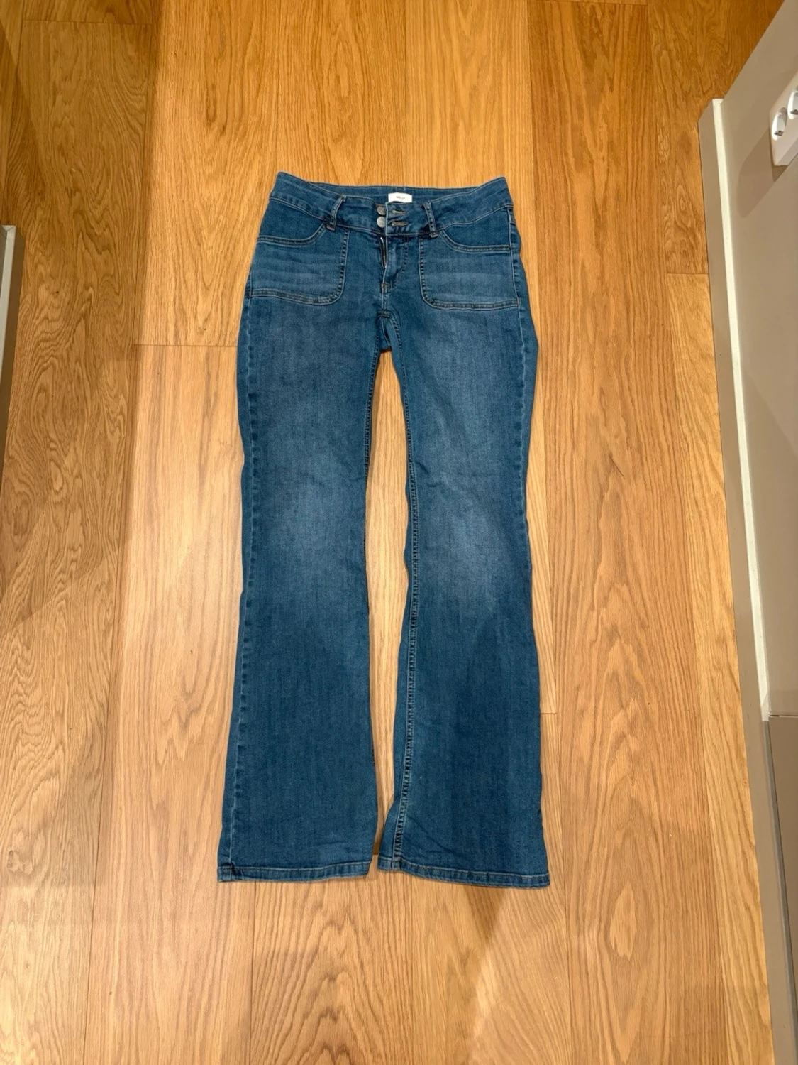 Blå bootcut jeans med knappar på fickorna