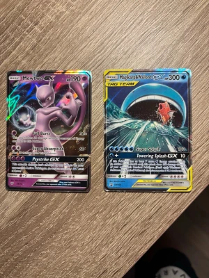 Pokémon GX-kort Mewtwo & Magikarp/Wailord - Två Pokémon GX-samlarkort: Mewtwo GX med lila och svarta detaljer samt Magikarp & Wailord GX Tag Team med blå och gula inslag. Båda korten har holografisk finish och är tryckta på klassiskt Pokémon-kortmaterial.