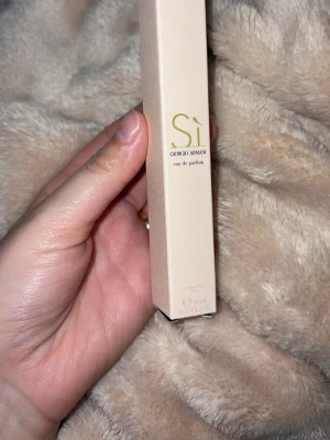 Giorgio Armani Sì Eau de Parfum 10ml - Säljer en lyxig och elegant parfym från Giorgio Armani, Sì Eau de Parfum. Kommer i en smidig 10 ml glasflaska med beige kartong. Perfekt att ha med i väskan för en fräsch doft när som helst.