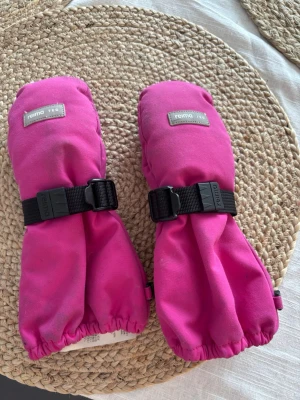 Rosa vinter handskar  från Reima - Säljer ett par rosa vinter handskar från Reima med svart greppyta i handflatan och justerbart spänne vid handleden. Perfekta för kalla dagar och håller händerna varma och torra. Snygg och funktionell design som passar till vinteroutfits. Storlek 3, 3-4 år Reima tec ote 