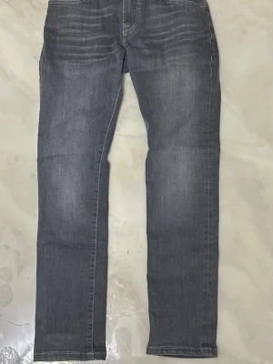 Scotch soda jeans - Snygga grå jeans med raka ben och diskreta slitningar vid låren. Klassisk femficksmodell med bakfickor och ljus tvätt. Perfekta för en avslappnad stil och passar till det mesta. Materialet är denim i bomull.