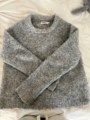 Grå fluffig stickad tröja från ONLY - Mysig grå stickad tröja från ONLY med fluffig textur och rund hals. Ge gärna prisförslag