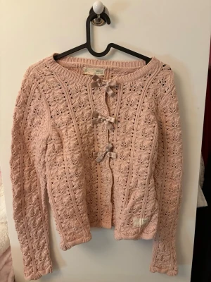 Rosa stickad kofta Odd Molly - Supersöt rosa stickad kofta från Odd Molly med fina virkade detaljer och tre sidenrosetter framtill. Koftan har rund halsringning och långa ärmar. Koftan är i fint skick och har inga speciella tecken på användning!❣️