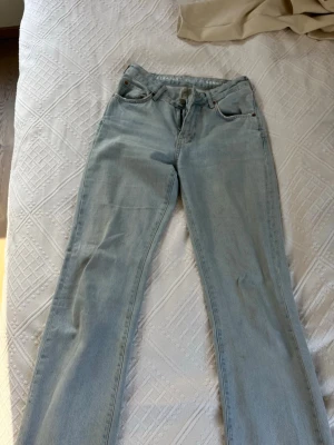Ljusblå raka jeans - Säljer ett par ljusblå jeans med rak passform och klassisk femficksdesign. Jeansen har normal midja och stängs med dragkedja och knapp. Perfekta för en avslappnad och trendig look. Storlek W 25, L 32
