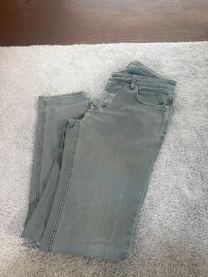 Två par slim fit jeans i blått och grått - Säljer två par slim fit jeans i snygga tvättade färger, ett par i grått och ett par i mörkblått. Klassisk femficksmodell med dragkedja och knapp. Perfekta för en avslappnad och trendig look. Materialet är bomullsdenim med lite stretch för extra komfort.