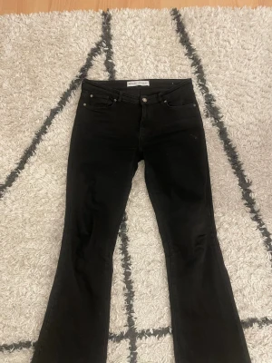 Svarta mid rise flared jeans från Bershka - Säljer ett par svarta flared jeans från Bershka. Jeansen har klassisk femficksmodell, mid rise midja och utsvängda ben. Tillverkade i stretchigt denimtyg för skön passform. Färgen försvinner inte vilket är det jag gillar mest med jeansen. 