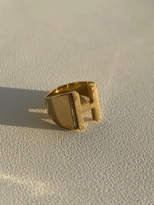 Guldring med H-design - Cool guld ring i rostfrittstål. Storleken går att justera. Säljer den då jag har bytt till silversmycken ❣️köpt i Madrid ☀️