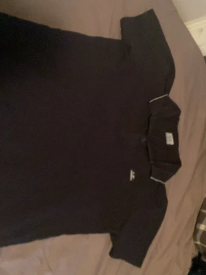 Mörkblå piké från C.P. Company - Mörkblå pikétröja från C.P. Company med klassisk krage, två knappar och diskret logga på bröstet. Enkel och stilren design som funkar till det mesta. (Knappt använd) storlek S