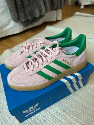 Adidas Spezial rosa/gröna sneakers - Säljer ett par Adidas Spezial sneakers i rosa mocka med gröna detaljer och klassiska tre ränder på sidan. Används 1 gång så superbra skick. Nypris 1349kr