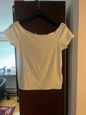 Ny vit ribbad offshoulder topp från Lager 157 - Ny vit ribbad topp från Lager 157 med offshoulder-design och korta ärmar. Tillverkad i mjukt och stretchigt material som sitter snyggt och bekvämt. Något liten i storleken.