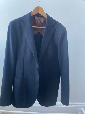 Blå kavaj från Oscar Jacobson - Blå kavaj från Sartorial Leisure by Oscar Jacobson i stlk 46 Fint skick men hål på armbågarna (se bilder). Pris kan diskuteras 