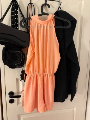 Korall färgad byxdress  - Korall färgad byxdress med halterneck. Halv öppen rygg, perfekt till sommaren. 💓