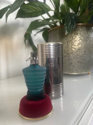 Jean Paul Gaultier Le Male parfym - Jean Paul Gaultier Le Male parfym i den ikoniska blå-randiga flaskan formad som en manlig torso. Flaskan står på en röd bas och kommer med original metallburk. Perfekt för dig som gillar unika och snygga parfymflaskor. (Sprillans ny)!