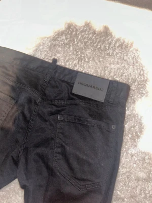 Svarta jeans från Dsquared2 - Snygga svarta jeans från Dsquared2 med klassisk femficksdesign och raka ben. Jeansen har en stilren look med svart läderpatch med logga bak i midjan. Perfekta för dig som gillar en clean och modern stil.