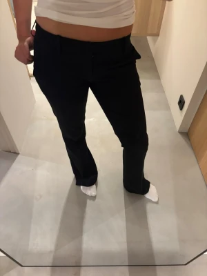 Svarta kostymbyxor med rak passform - Snygga svarta kostymbyxor med rak passform och klassisk midja. Byxorna har diskreta fickor och stängs med knapp och dragkedja. Perfekta för en clean och stilren look🌸