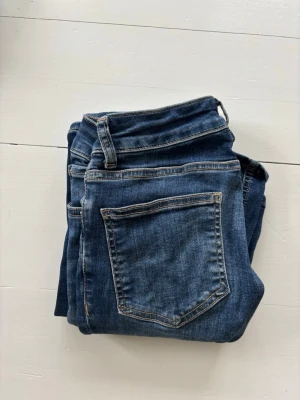 Blå jeans från 157 Blaze - Snygga blå jeans från 157 Blaze i strl xs tall som är riktigt lågmidjade, med klassisk femficksmodell och flare/bootcut brn. Jeansen har kontrastsömmar och bälteshällor, perfekta till en avslappnad stil. Tillverkade i mjukt denimtyg som ger en skön känsla hela dagen.