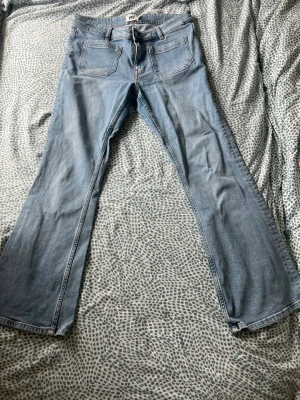 Blå bootcut jeans från lagger157 - Säljer ett par ljusblå bootcut jeans från H&M med klassisk femficksdesign och normal passform. Jeansen har en snygg utsvängd siluett och är tillverkade i mjuk bomull. Perfekta för en avslappnad och trendig look.