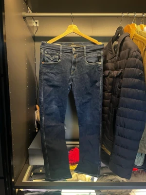 Mörkblå raka jeans från Replay - Säljer ett par mörkblå jeans från Replay med raka ben och klassisk femficksdesign. Jeansen har kontrastsömmar och metallknappar. Perfekta för dig som gillar en tidlös och stilren look. Materialet är denim i bomull. Bra skick då de endast använts vid ett fåtal tillfällen
