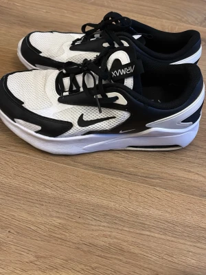 Nike Air Max vita och svarta sneakers - Snygga Nike Air Max sneakers i vitt och svart med klassisk swoosh-logga på sidan. Ovandelen är i mesh och syntet för bra andningsförmåga och komfort. Tjock sula med synlig Air Max-dämpning ger skön känsla och street-look. Perfekta för dig som gillar sportig stil.