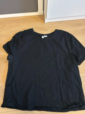 Svart basic t-shirt i bomull - Enkel svart t-shirt i mjuk bomull med rund hals och korta ärmar. Perfekt till jeans eller shorts för en clean och avslappnad stil. Klassisk passform och utan tryck eller mönster.
