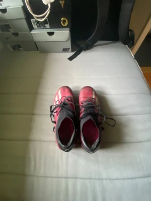 Adidas X speedportal Elite FG - Säljer ett par snygga Adidas fotbollsskor i rosa och svart med vita detaljer. Skorna har klassiska dobbar för bra grepp på planen och snörning för optimal passform. Ovandelen är i syntetmaterial och designen är sportig och modern. Perfekta för dig som vill sticka ut på planen.